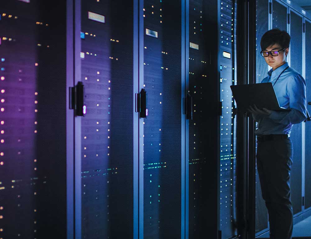 Cloud Computing student with laptop in front of server bank