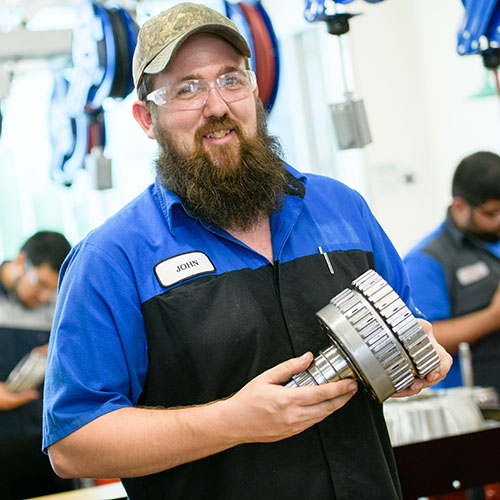 ford asset student, john, holding car part for camera