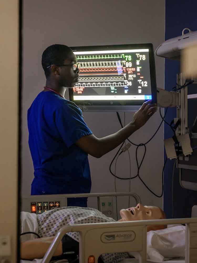 male nurse checking vitals for mannequin patient on bed