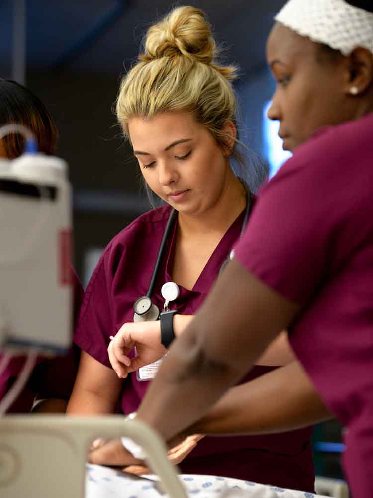 two female nurses working together to do chest compressions on patient