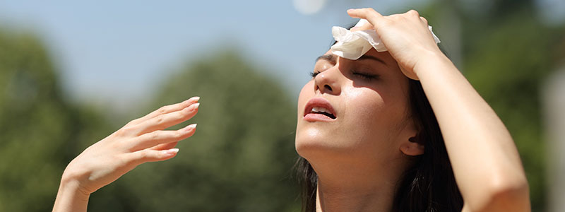Woman wipes sweat from forehead in hot weather